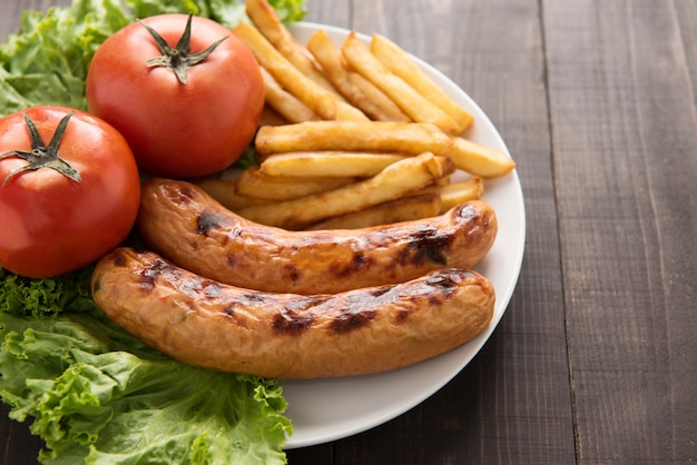 Salsiccia e verdure arrostite con le patate fritte su fondo di legno