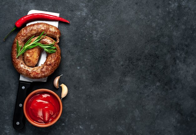 Salsiccia fritta a spirale con spezie su un coltello da carne