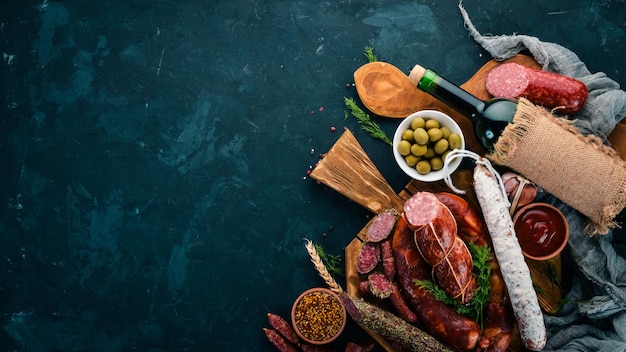 Salsiccia Fuet salame cartone sul bordo della cucina su sfondo nero Vista dall'alto Spazio libero per il testo