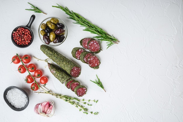 Salsiccia fuet Traditianal alle erbe con ingredienti sulla superficie bianca, vista dall'alto con lo spazio della copia