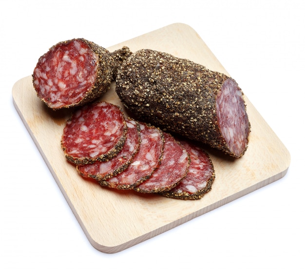 Salsiccia organica secca del salame coperta di pepe sul bordo di servizio di legno