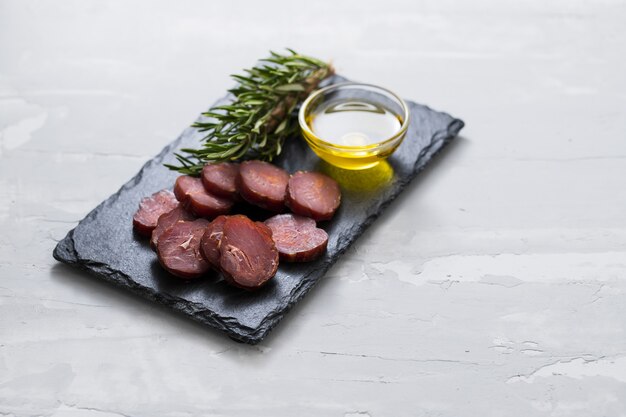 Salsiccia portoghese affumicata con olio d'oliva e rosmarino a bordo nero