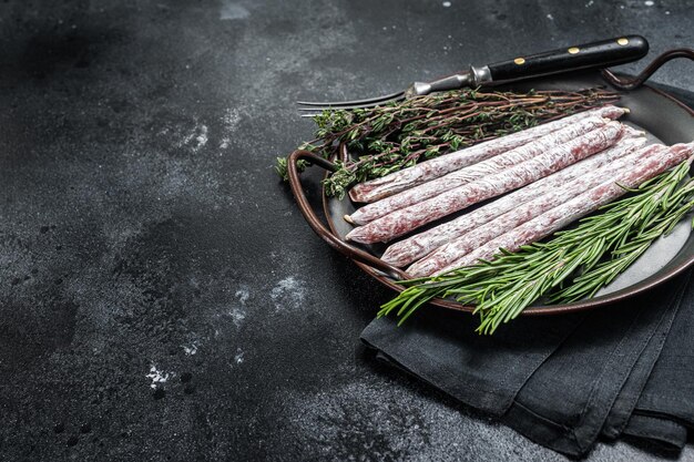 Salsiccia spagnola di tapa mini fuet con erbe Sfondo nero Vista dall'alto Spazio di copia