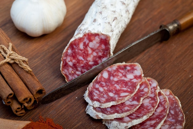 Salsiccia stagionata del salame italiano tradizionale affettata su una tavola di legno