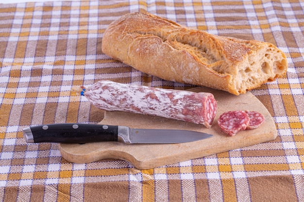 Salsiccia su un tagliere di legno su una tovaglia di piastrelle