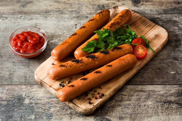 Salsiccie arrostite e ketchup su una tavola di legno