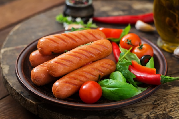 Salsiccie arrostite e verdure su una tavola di legno nello stile rustico.