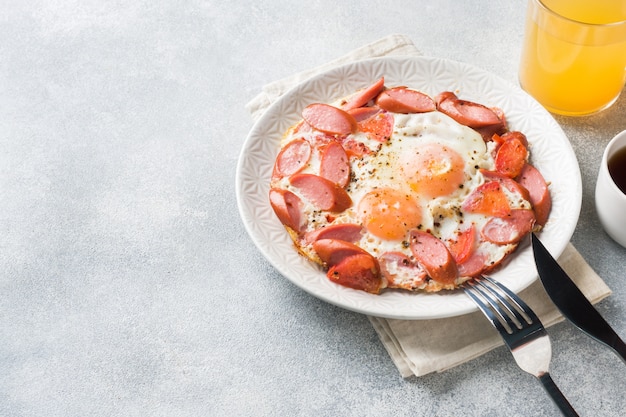 Salsiccie e pomodori delle uova fritte su un piatto sulla tavola.