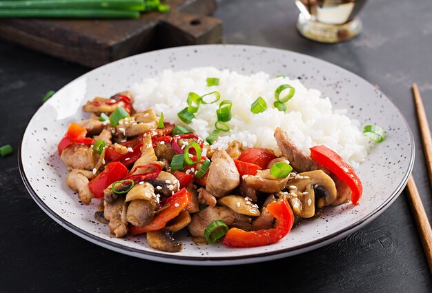 Saltare in padella con pollo, funghi, peperoni dolci e riso bollito. Cibo cinese.