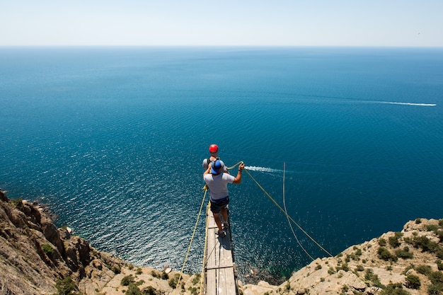 Salto con la corda da una scogliera con una corda nell'acqua. L'oceano. Mare. Montagna