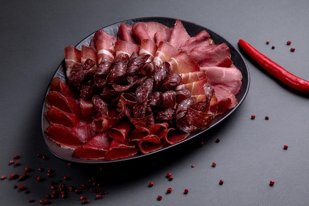 Salumi su piatto nero su fondo scuro decorato