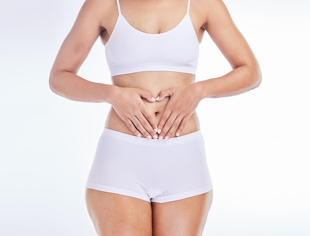 Salute cuore e mani sullo stomaco della donna per allenare la nutrizione e l'equilibrio del benessere intestinale Mestruazioni digestione e fitness con il corpo della ragazza per i probiotici dietetici o la depilazione su sfondo bianco