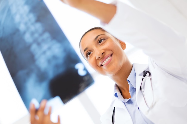 salute e concetto di medicina - dottoressa sorridente che studia raggi x