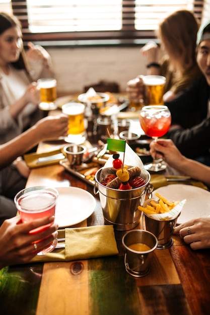 Saluti mano che tiene tazze con birra sopra il tavolo