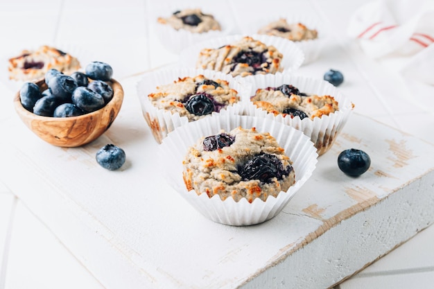 Saluti muffin di cocco con mirtilli Solo quattro ingredienti farina di cocco uova banana e mirtilli su sfondo bianco