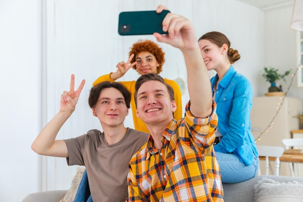 Saluti, umore funky, un gruppo felice di amici fa selfie con un uomo che scatta foto di amici al gruppo di festa di