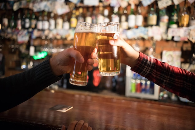 Saluti un primo piano di due uomini che brindano con la birra al bancone del bar