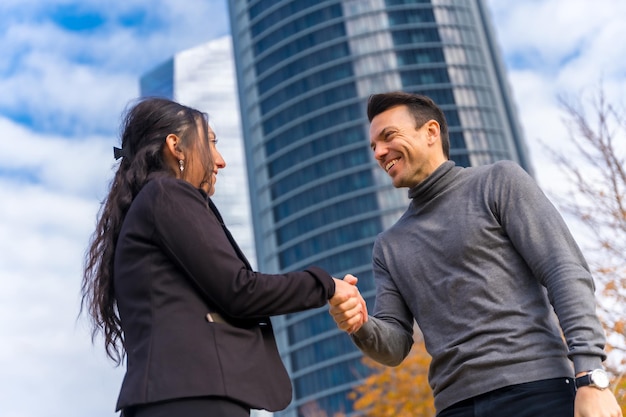 Saluto multietnico dell'uomo d'affari e della donna di affari agitando le mani e sorridendo