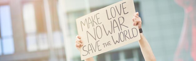 Salva il mondo felice giovane attivista maschio che tiene striscione o poster sopra la testa mentre protesta
