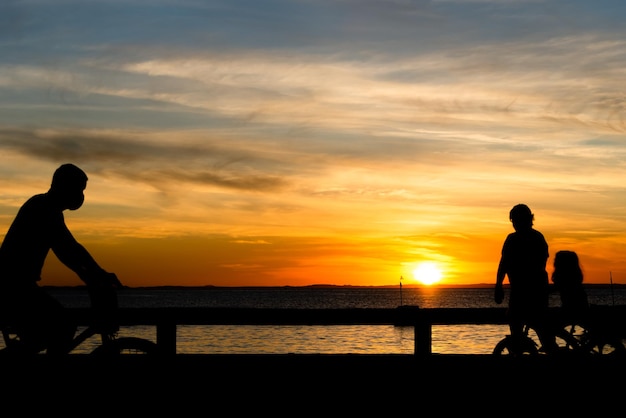 Salvador, Bahia, Brasile - 27 maggio 2021: silhouette di persone che camminano, corrono, vanno in bicicletta, parlano e si godono il tramonto sulla spiaggia di Ribeira.