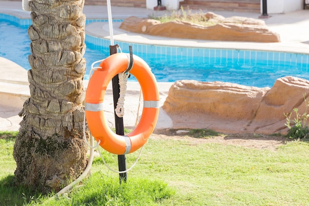 Salvagente di emergenza arancione appeso alla recinzione vicino alla piscina in vacanza in hotel con spazio per la copia