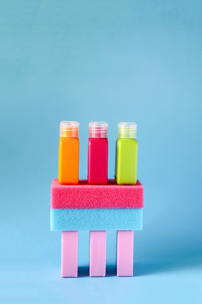 Salviette colorate, bottigliette da viaggio in plastica per liquidi e saponette su uno sfondo blu morbido. Set di accessori per la cura e l'igiene del corpo.