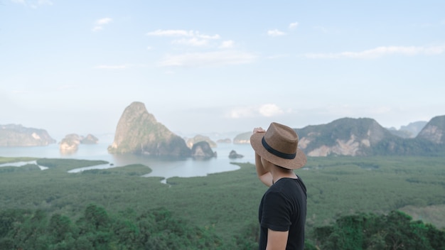 Samed Nang Chee. Uomo con vista sulla baia di Phang Nga, foresta di mangrovie e colline sul mare delle Andamane, Thailandia.