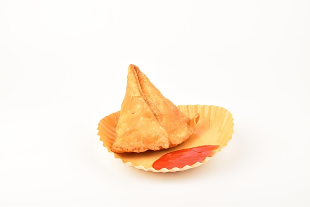 Samosa con salsa in piatto isolato su sfondo bianco