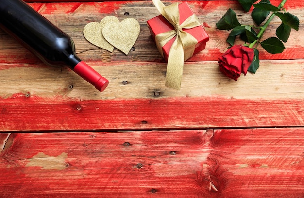 San Valentino Bottiglia di vino rosso rosa e un regalo su sfondo di legno