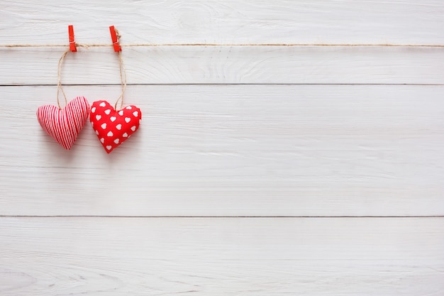 San Valentino con cuscino cucito coppia di cuori fatti a mano fai da te su mollette rosse a assi di legno bianco rustico