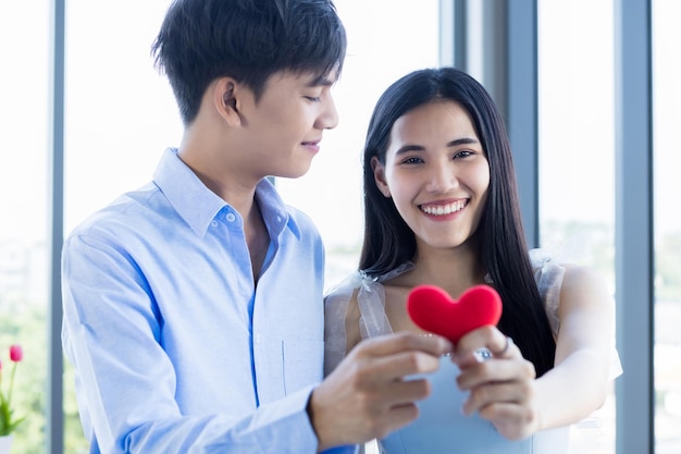 San Valentino conceptasian Giovane coppia dolce felice mostra innamorata Sfocatura astratta con focus mostra tenendo piccolo un cuscino a forma di cuore rosso Dopo pranzo In uno sfondo di ristorante