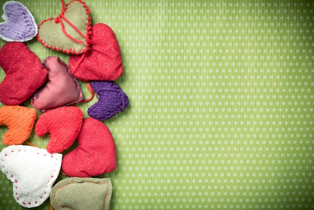 San Valentino. Cuori lavorati a maglia colorati su un'annata verde a pois. Cuore rosso.