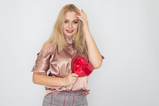 San Valentino - donna di sogno in camicetta rosa che tiene cuore rosso del contenitore di regalo