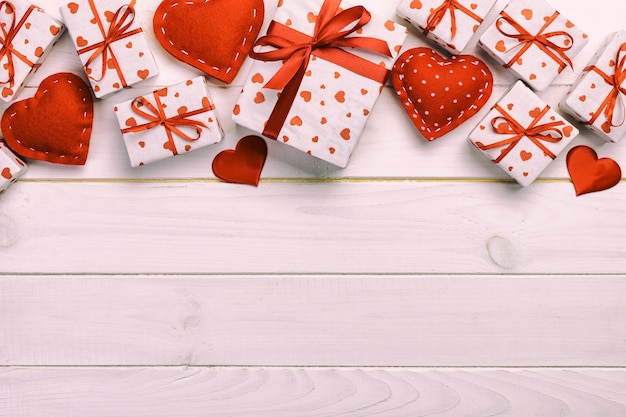 San Valentino o altra vacanza regalo fatto a mano in carta con cuori rossi e confezione regalo in involucro festivo. Regalo attuale della scatola sulla vista di legno bianca del piano d'appoggio con lo spazio della copia, spazio vuoto per progettazione