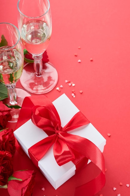 San Valentino o concetto di cena romantica Tavolo romantico apparecchiare argenteria bicchieri di vino scatola regalo rose e simbolo di amore cuore rosso su sfondo rosso Cena romantica concetto di San Valentino