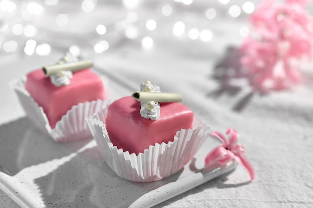 San Valentino petit fours con glassa di marzapane. Fiore di giacinto rosa profumato. Ghirlanda di luci su tessuto bianco. Serata romantica a casa. Buon San Valentino!