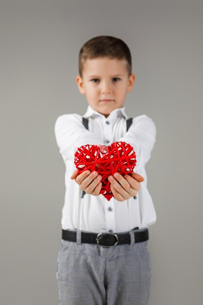 San Valentino. Ritratto di ragazzo carino bambino con cuore rosso isolato su sfondo grigio