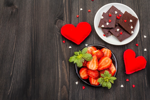 San Valentino romantico concetto. Cioccolato, fragola fresca matura, cuori di feltro rosso. Dessert dolce per gli amanti.