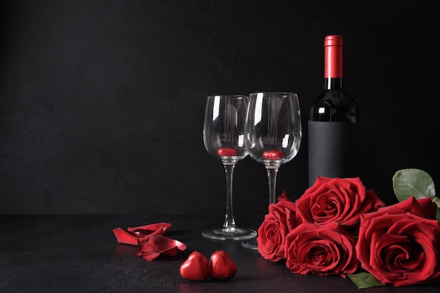 San Valentino romantico set di vino rosso e bouquet di rose rosse, cuori dolci sul nero. Biglietto di auguri con copia spazio. Incontri romantici. Proposta.