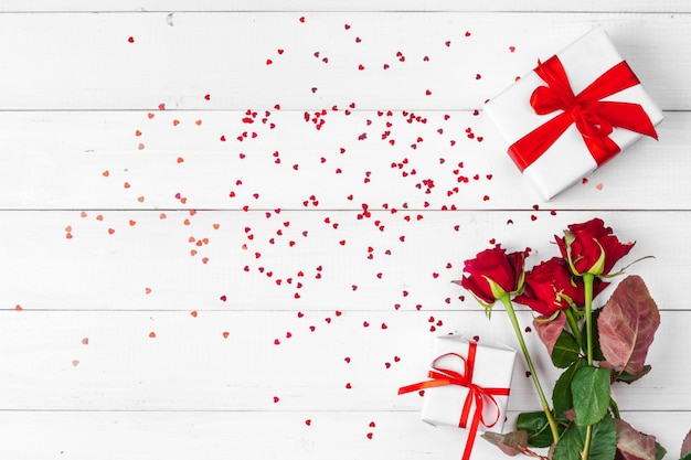 San Valentino. Rose rosse e contenitore di regalo sulla tavola di legno