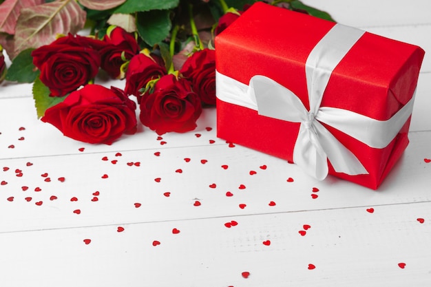 San Valentino. Rose rosse e contenitore di regalo sulla tavola di legno