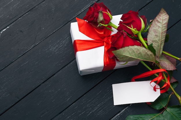 San Valentino. Rose rosse e contenitore di regalo sulla tavola di legno