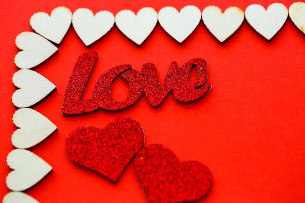 San Valentino sfondo rosso con cuori in legno e la parola amore. Posto per iscrizioni, pubblicità