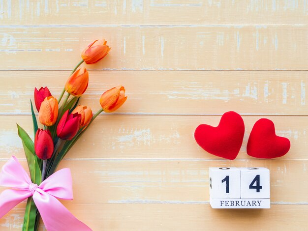 San Valentino sullo sfondo. Cuore rosso, calendario in legno 14 febbraio, fiori su fondo in legno.