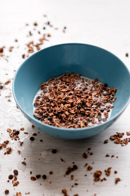 Sana colazione a base di cereali. Granola dolce con latte in ciotola verde acqua