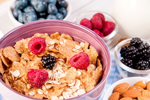 Sana colazione con bacche di cornflakes, latte e mandorle noci sul tavolo di legno