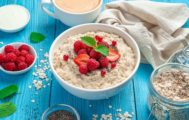 Sana colazione con farina d'avena con lamponi fragole ribes rosso su sfondo blu