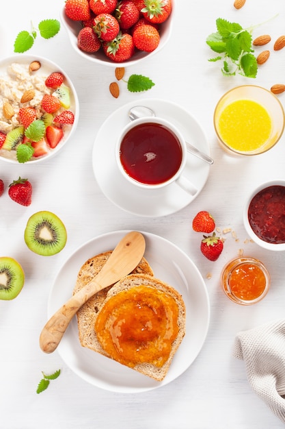 Sana colazione con porridge di farina d'avena, fragole, noci, toast, marmellata e tè. Vista dall'alto