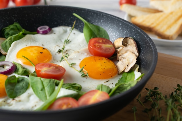 Sana colazione con uova fritte, pomodori, funghi e foglie di spinaci