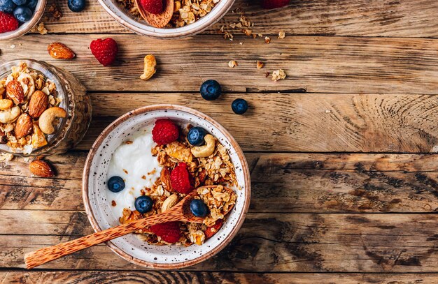 Sana colazione con yogurt e muesli al forno con frutti di bosco in due piccole ciotole Muesli al forno con noci, olio di cocco e miele